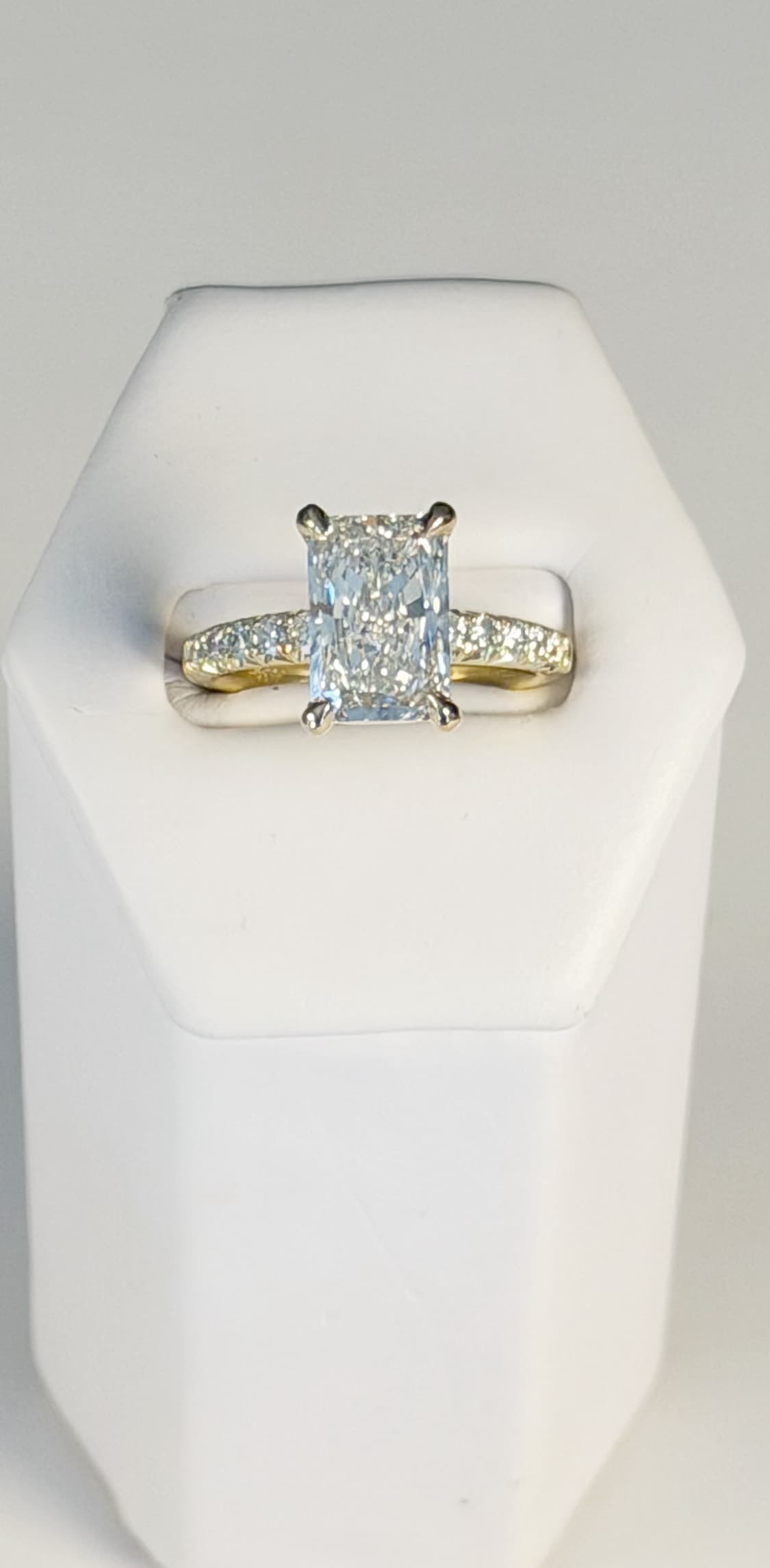 Radiant-cut diamond solitaire with a pavé band, two-tone white and yellow gold