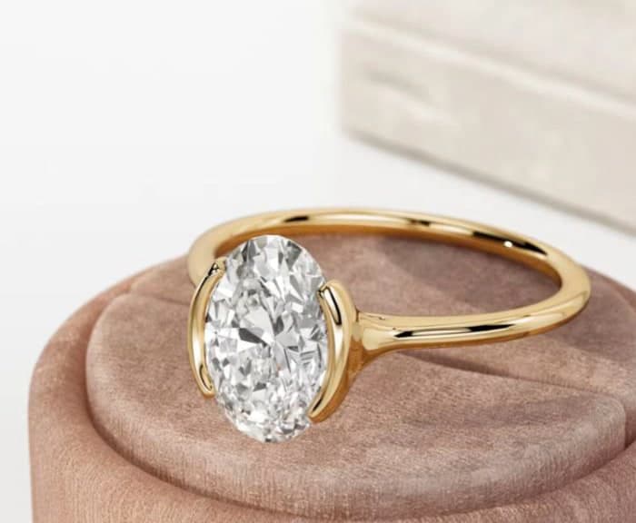Oval brilliant solitaire in yellow gold on a rose velvet ring stand