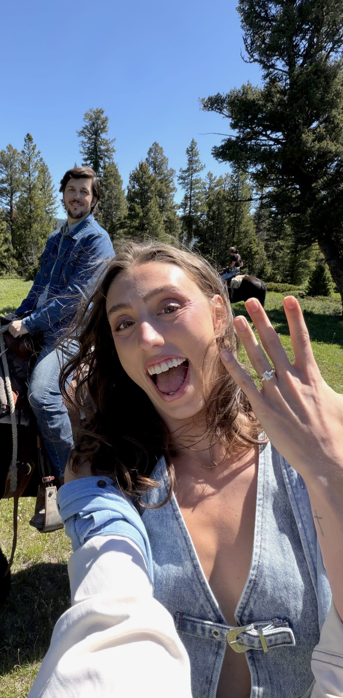 Newly-engaged customer showing off her emerald-cut diamond ring on horseback in the Montana mountains