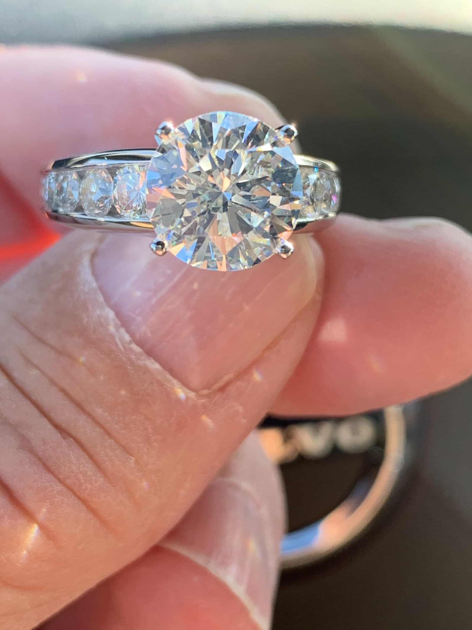 Round brilliant ring with channel-set pavé band in sunlight